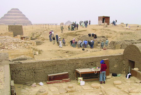 Počáteční fáze odkrývání hrobky kněze Merinejta. Na obzoru vlevo se tyčí nejstarší egyptská pyramida faraona Džosera. Foto: Ladislava Horáčková. Počáteční fáze odkrývání hrobky kněze Merinejta. Na obzoru vlevo se tyčí nejstarší egyptská pyramida faraona Džosera. Foto: Ladislava Horáčková.